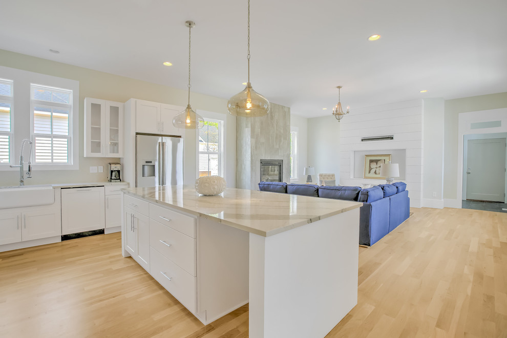 Example of a mid-sized transitional l-shaped light wood floor open concept kitchen design with a farmhouse sink, shaker cabinets, white cabinets, stainless steel appliances, an island and quartzite countertops