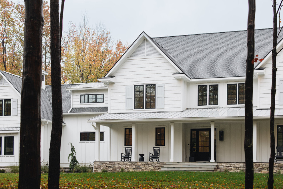 Exterior - Modern farmhouse exterior near Grand Rapids, Michigan featuring a stone porch, board and batten siding, shutters, black windows, gray shingle roof, and black front door.