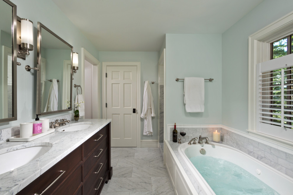 Inspiration for a mid-sized transitional master bathroom in New York with shaker cabinets, dark wood cabinets, a drop-in tub, blue walls, porcelain floors, an undermount sink, granite benchtops, grey floor, multi-coloured benchtops, a double vanity and a built-in vanity.