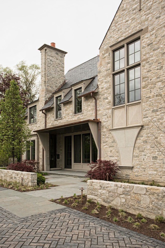 Photo of a large transitional three-storey beige house exterior in Chicago with stone veneer and a tile roof.