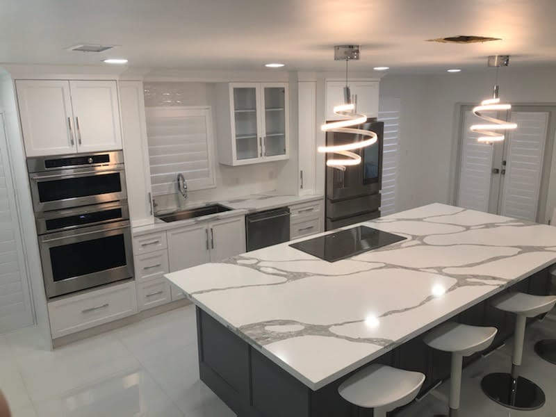 Eat-in kitchen - transitional single-wall porcelain tile and white floor eat-in kitchen idea in Miami with an undermount sink, shaker cabinets, white cabinets, quartz countertops, white backsplash, mosaic tile backsplash, stainless steel appliances and an island