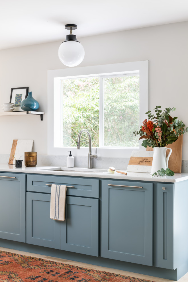Inspiration for a mid-sized transitional u-shaped light wood floor eat-in kitchen remodel in Atlanta with an undermount sink, shaker cabinets, blue cabinets, blue backsplash, ceramic backsplash, paneled appliances and white countertops