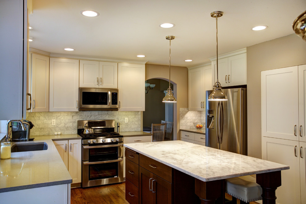 Inspiration for a mid-sized transitional l-shaped medium tone wood floor eat-in kitchen remodel in Seattle with an undermount sink, recessed-panel cabinets, white cabinets, quartz countertops, white backsplash, stone tile backsplash, stainless steel appliances and an island