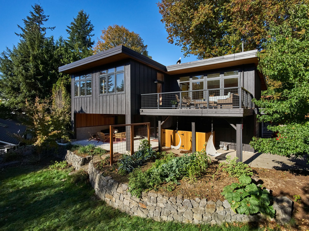 Design ideas for a large midcentury two-storey black house exterior in Portland with wood siding, a butterfly roof and board and batten siding.