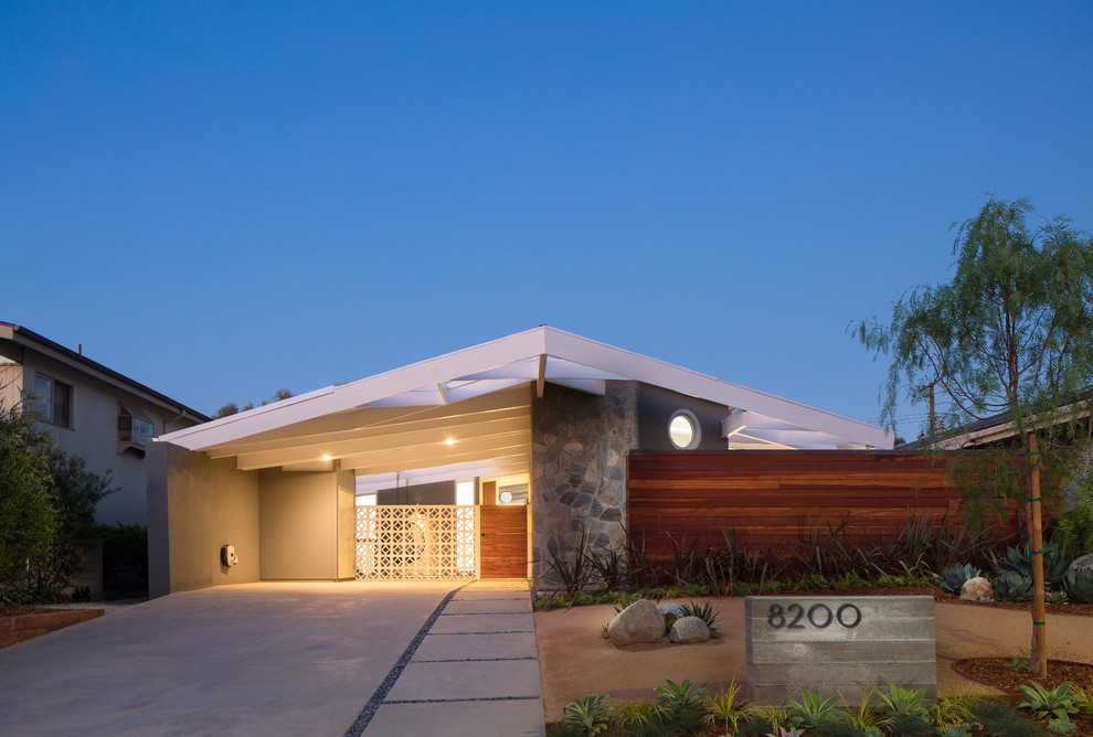 This is an example of a midcentury one-storey stucco beige house exterior in Los Angeles with a gable roof.