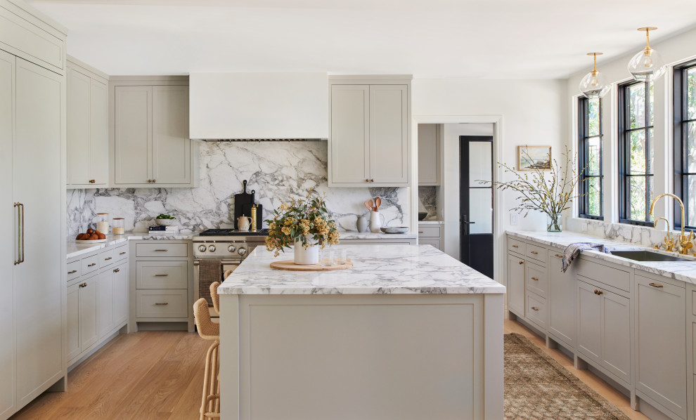 Photo of a transitional kitchen in Los Angeles with an undermount sink, shaker cabinets, beige cabinets, marble benchtops, multi-coloured splashback, marble splashback, panelled appliances, medium hardwood floors, with island and brown floor.