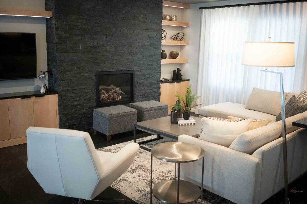 Стильный дизайн: большая открытая гостиная комната в стиле ретро с серыми стенами, полом из винила, стандартным камином, фасадом камина из камня и черным полом - последний тренд