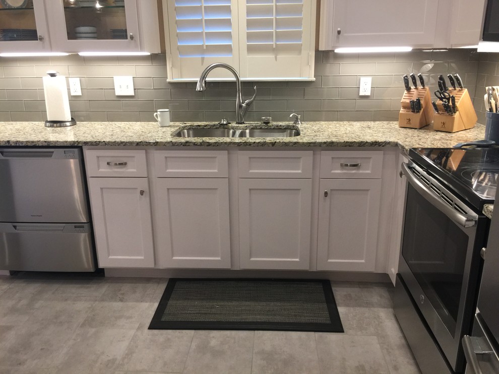 Mid-sized transitional l-shaped porcelain tile eat-in kitchen photo in Austin with an undermount sink, shaker cabinets, white cabinets, granite countertops, white backsplash, glass tile backsplash, stainless steel appliances and an island