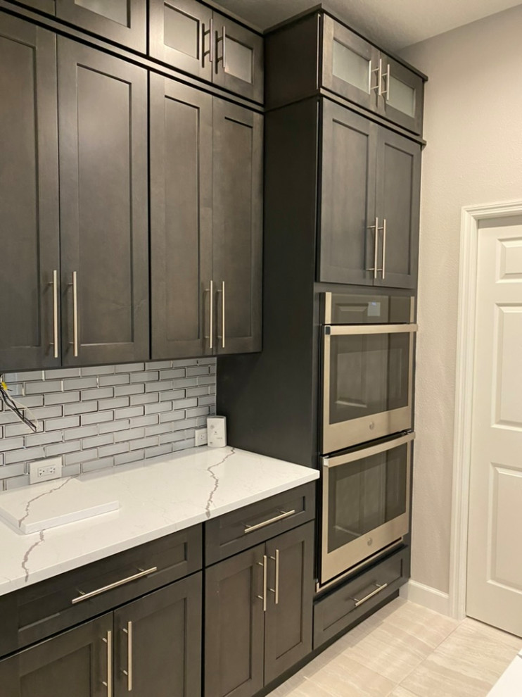 Inspiration for a large transitional porcelain tile and beige floor eat-in kitchen remodel in Tampa with a single-bowl sink, shaker cabinets, dark wood cabinets, quartzite countertops, gray backsplash, subway tile backsplash, stainless steel appliances, an island and white countertops