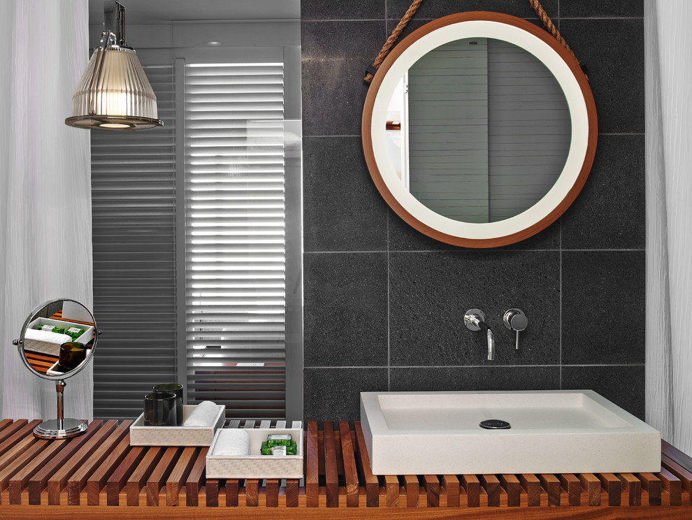 Bathroom - large contemporary gray tile and stone tile porcelain tile bathroom idea in Melbourne with a vessel sink, open cabinets, medium tone wood cabinets, wood countertops and gray walls
