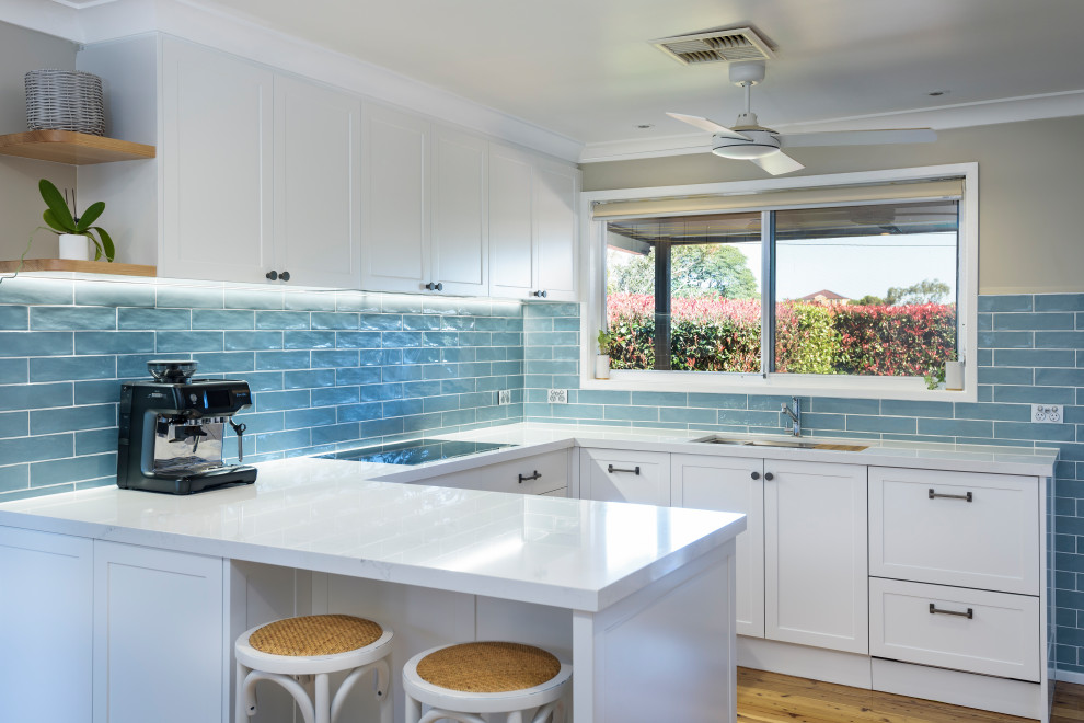 Photo of a small contemporary u-shaped kitchen/diner in Newcastle - Maitland with shaker cabinets, white cabinets, engineered stone countertops and white worktops.