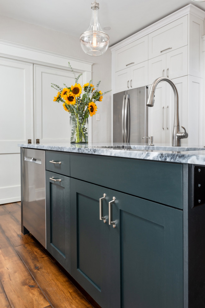 Mid-sized transitional galley medium tone wood floor and brown floor eat-in kitchen photo with a single-bowl sink, shaker cabinets, white cabinets, quartz countertops, gray backsplash, subway tile backsplash, stainless steel appliances, an island and white countertops