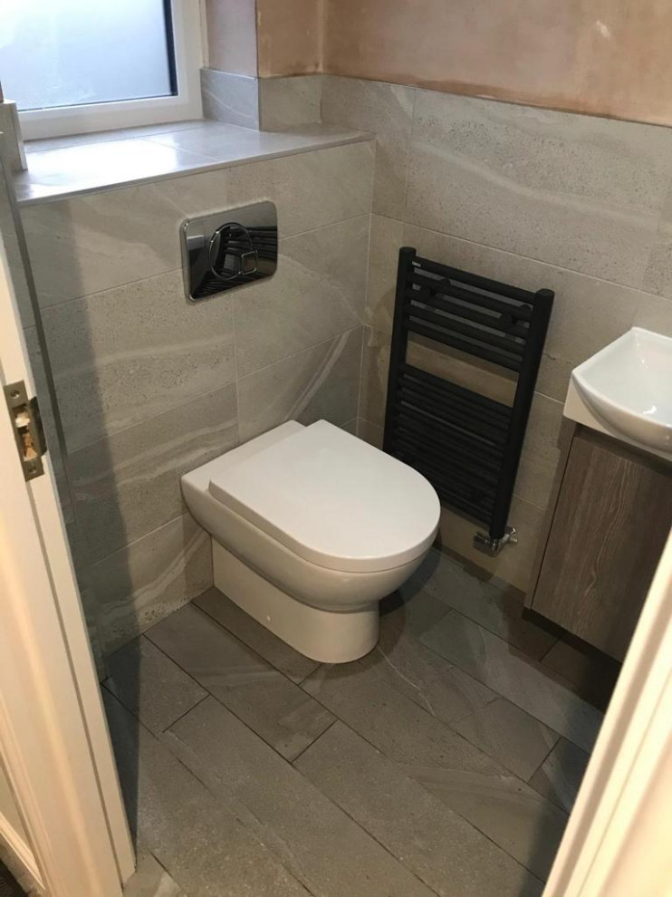 This is an example of a small contemporary bathroom in Manchester with flat-panel cabinets, grey cabinets, a one-piece toilet, gray tile, porcelain tile, porcelain floors, a wall-mount sink, grey floor, an enclosed toilet, a single vanity and a floating vanity.