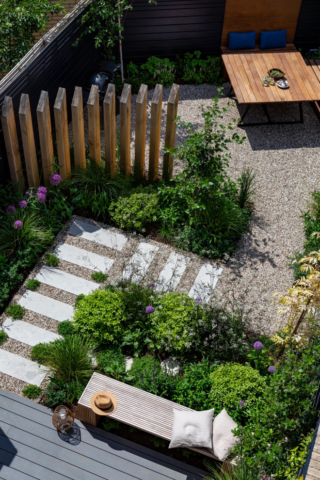 Réalisation d'un petit jardin arrière minimaliste au printemps avec une exposition ensoleillée, du gravier et une clôture en bois.
