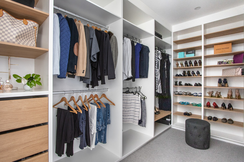 This is an example of a contemporary gender-neutral walk-in wardrobe in Sydney with open cabinets, light wood cabinets, carpet and grey floor.