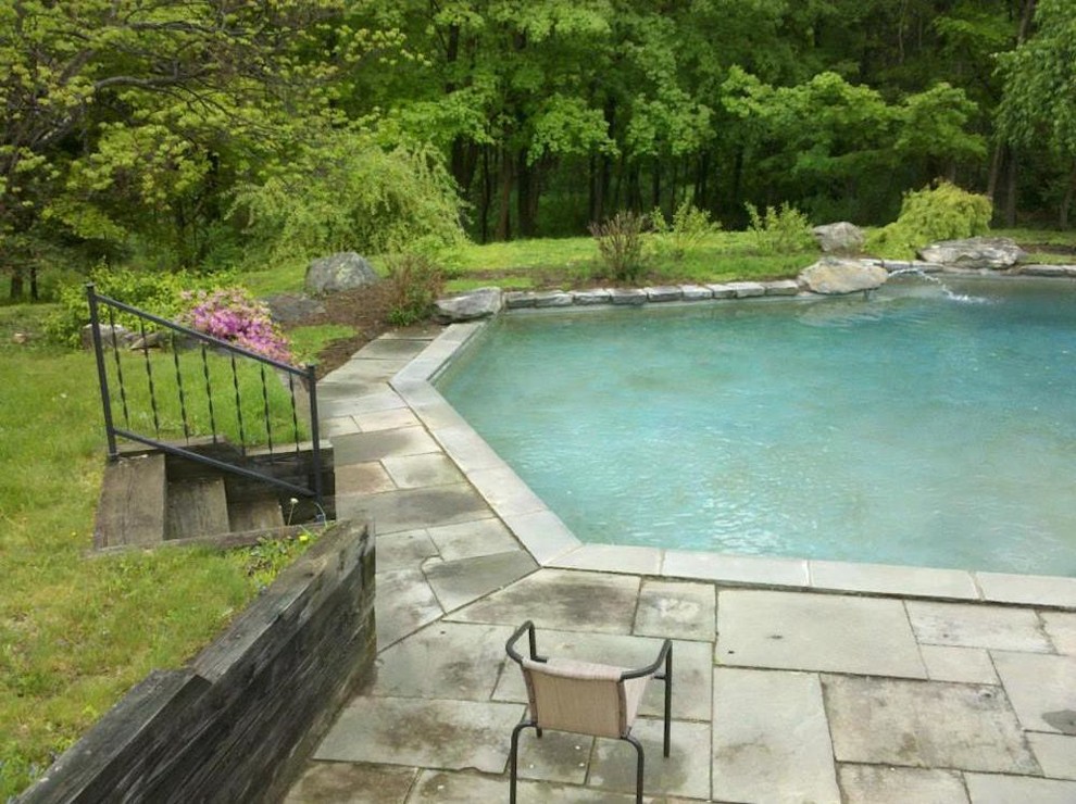 Example of a large transitional backyard stone and custom-shaped natural pool design in New York