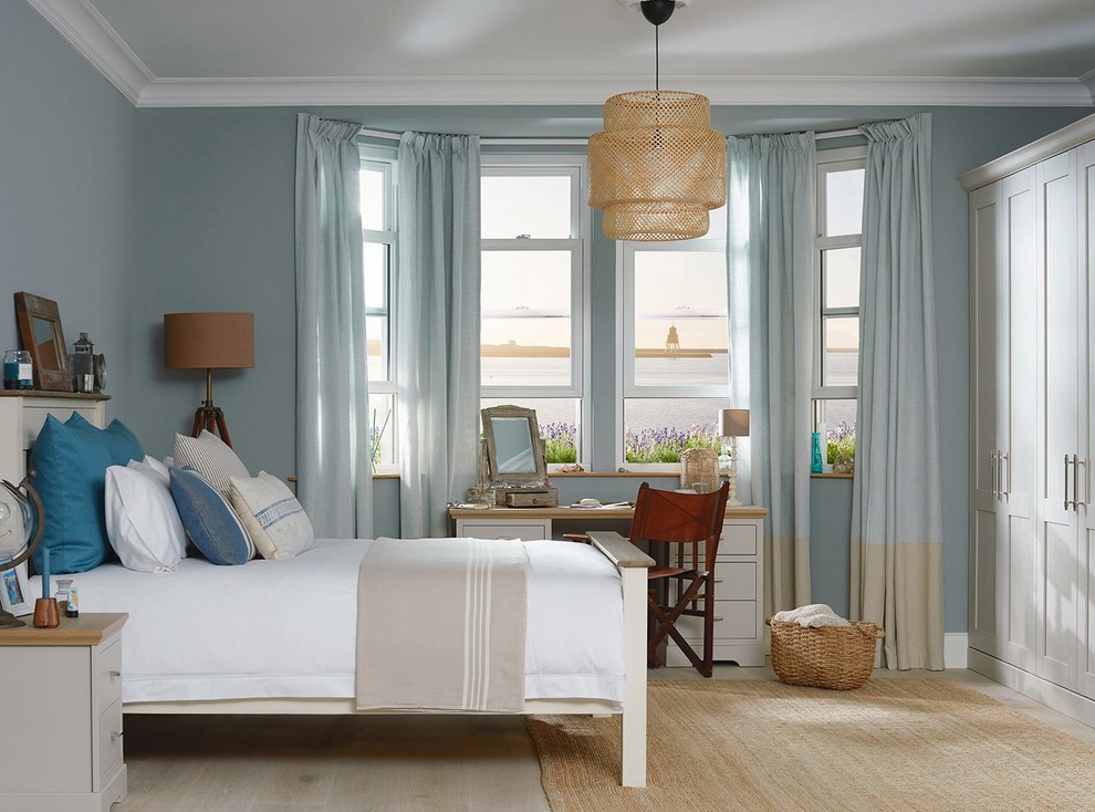 Inspiration for a mid-sized beach style master bedroom in Dublin with blue walls, light hardwood floors and beige floor.