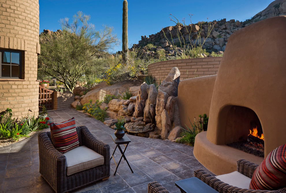 Design ideas for a mid-sized backyard patio in Phoenix with a fire feature, natural stone pavers and a roof extension.