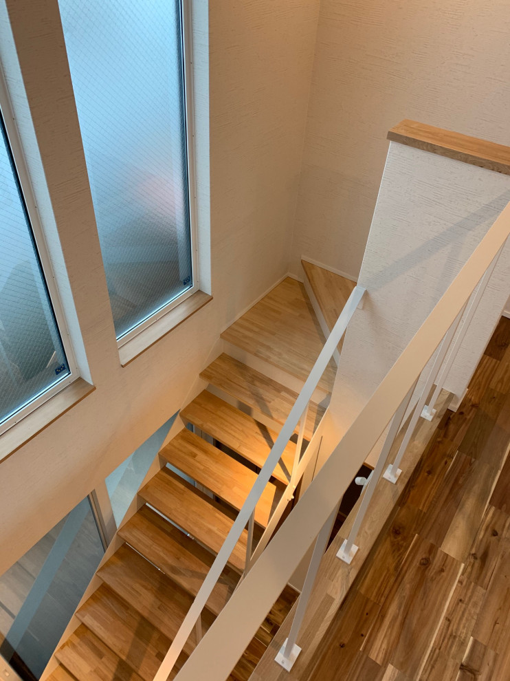 Modern straight staircase in Kyoto with open risers, metal railing and wallpaper.