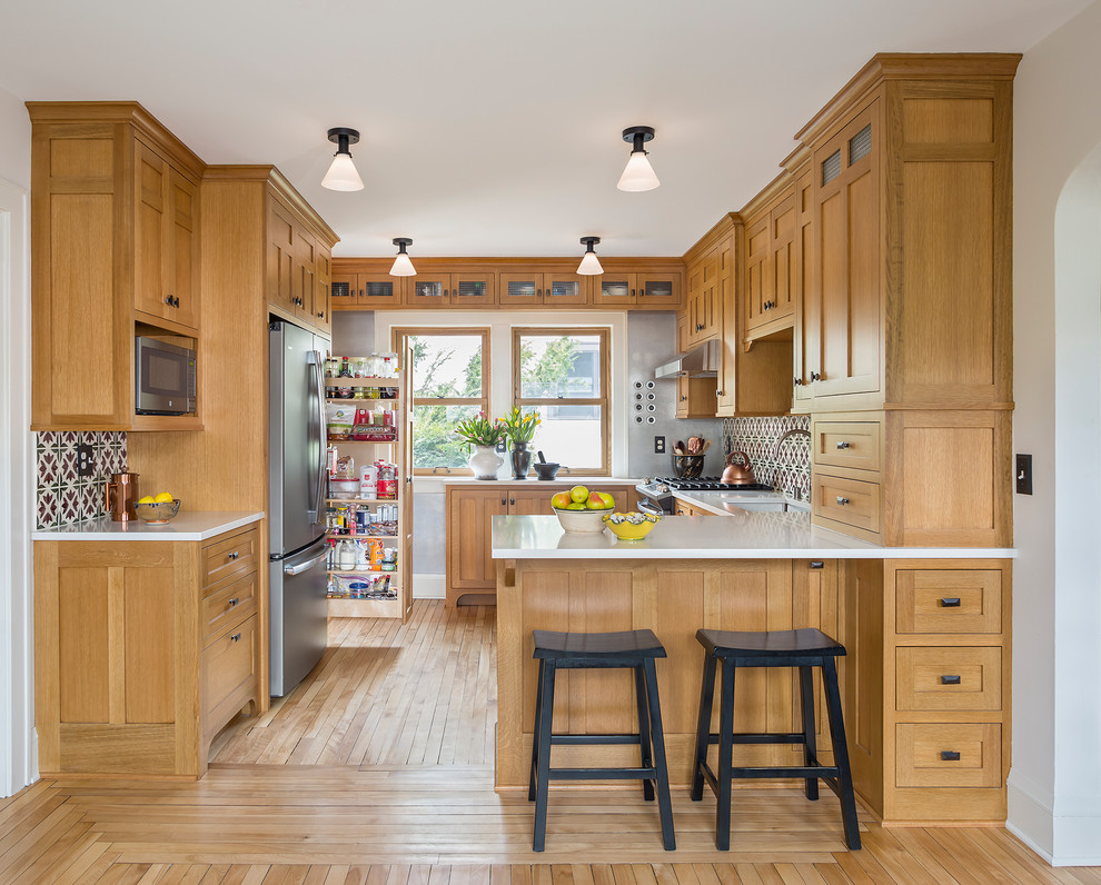 Inspiration for a small arts and crafts u-shaped eat-in kitchen in Minneapolis with an undermount sink, shaker cabinets, light wood cabinets, quartz benchtops, multi-coloured splashback, ceramic splashback, coloured appliances, light hardwood floors, no island, brown floor and white benchtop.