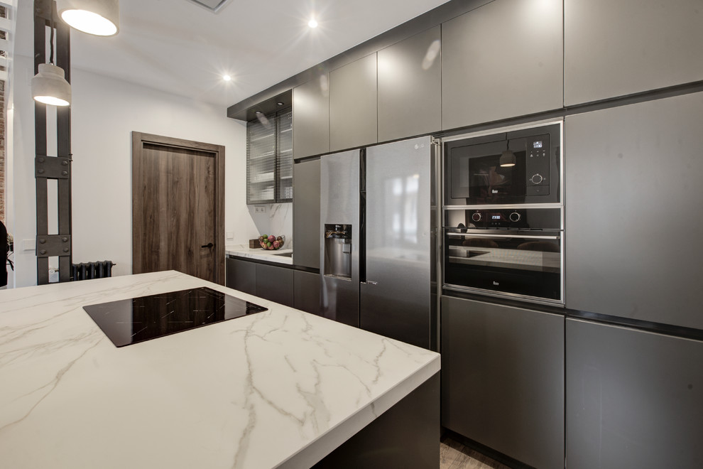 Inspiration for a mid-sized industrial open plan kitchen in Madrid with a single-bowl sink, glass-front cabinets, grey cabinets, marble benchtops, panelled appliances, laminate floors, with island and brown floor.