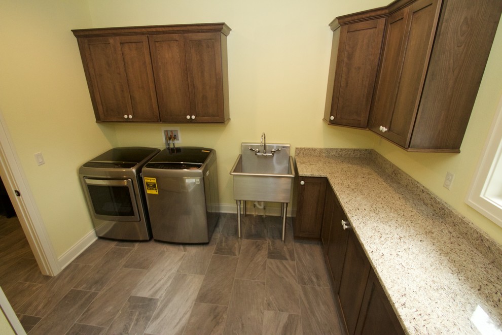 Design ideas for an expansive transitional l-shaped dedicated laundry room in Milwaukee with an utility sink, recessed-panel cabinets, medium wood cabinets, granite benchtops, yellow walls, medium hardwood floors and a side-by-side washer and dryer.