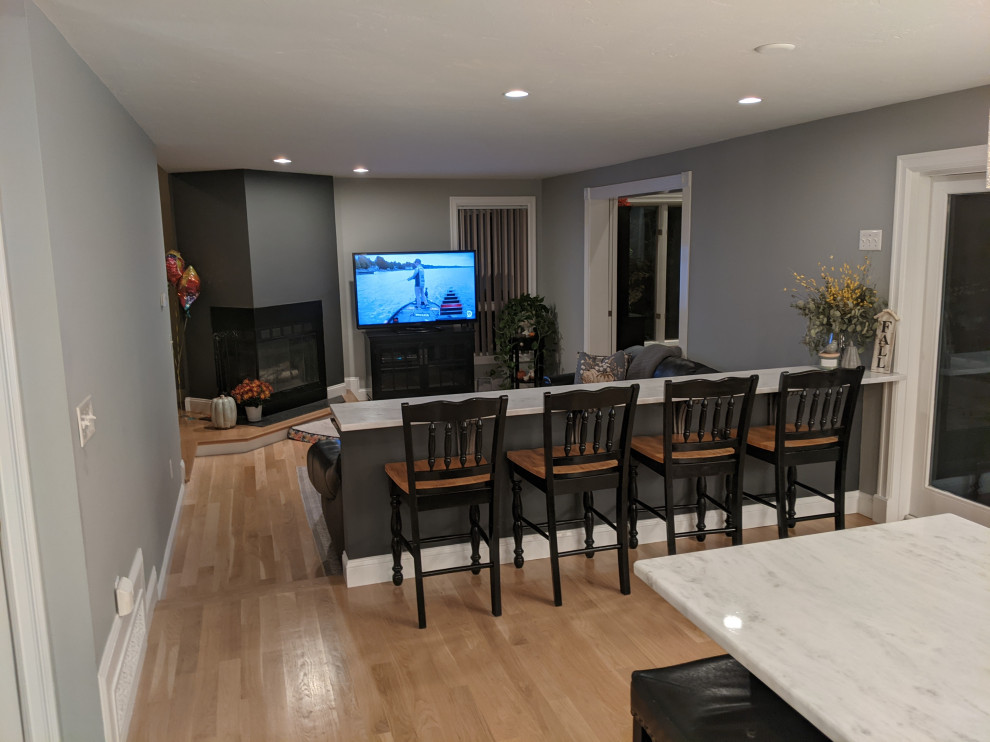 Huge transitional l-shaped light wood floor eat-in kitchen photo in Boston with an undermount sink, shaker cabinets, white cabinets, granite countertops, white backsplash, granite backsplash, stainless steel appliances, an island and white countertops