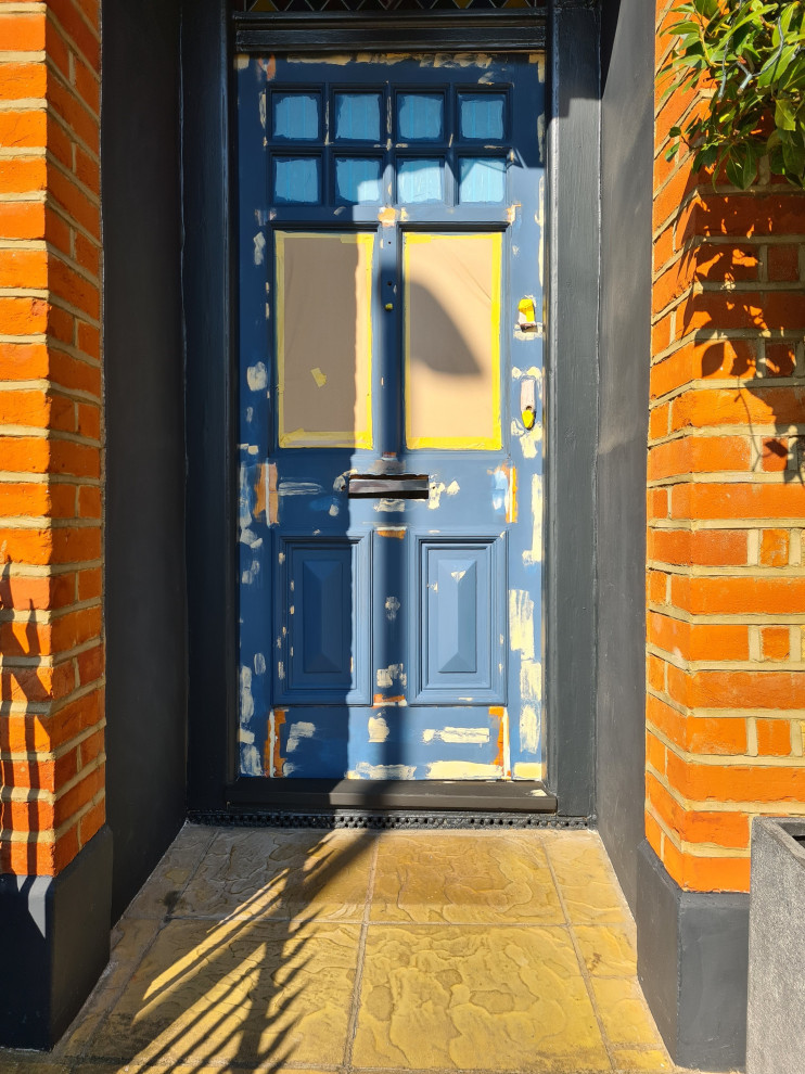 Mid-sized traditional front door in London with black walls, dark hardwood floors, a single front door, a black front door, brown floor and recessed.