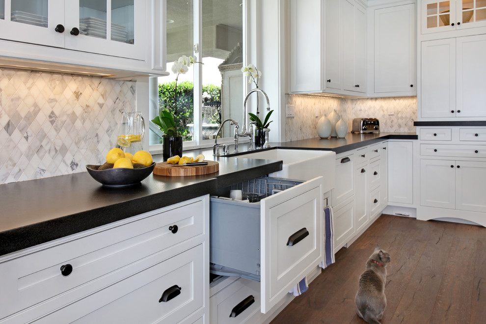 This is an example of a large transitional galley eat-in kitchen in Orange County with a farmhouse sink, shaker cabinets, white cabinets, quartz benchtops, white splashback, mosaic tile splashback, stainless steel appliances, medium hardwood floors and with island.