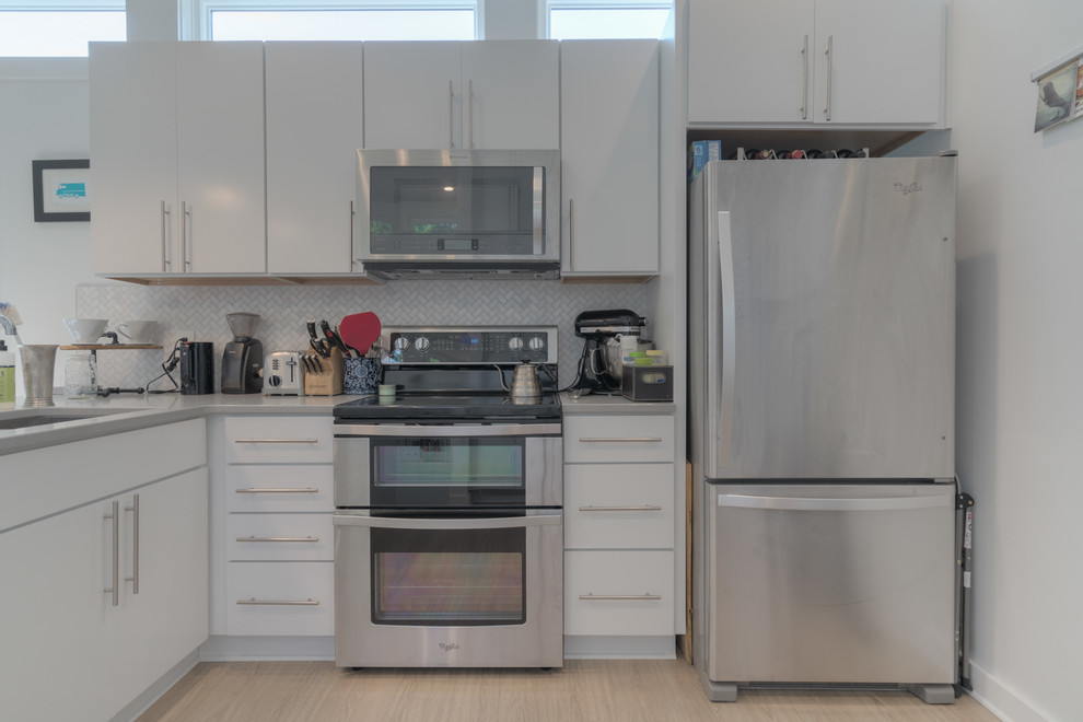 Inspiration for a small modern l-shaped vinyl floor and beige floor open concept kitchen remodel with an undermount sink, flat-panel cabinets, white cabinets, quartz countertops, gray backsplash, marble backsplash, stainless steel appliances and a peninsula