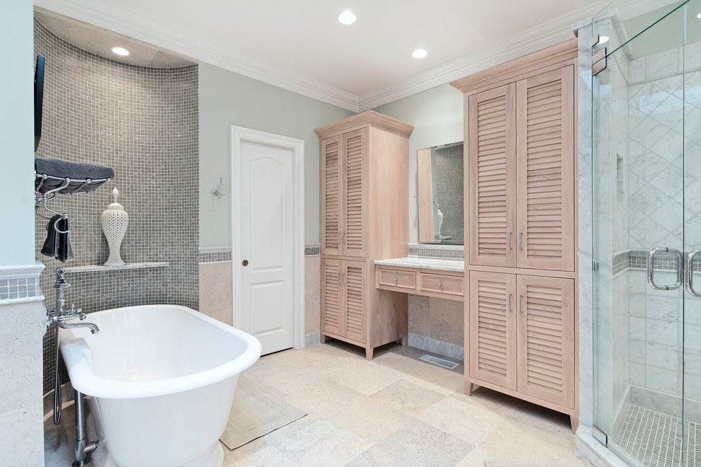 This is an example of a traditional bathroom in DC Metro with an undermount sink, louvered cabinets, light wood cabinets, marble benchtops, a freestanding tub, a corner shower, a two-piece toilet, gray tile and stone tile.