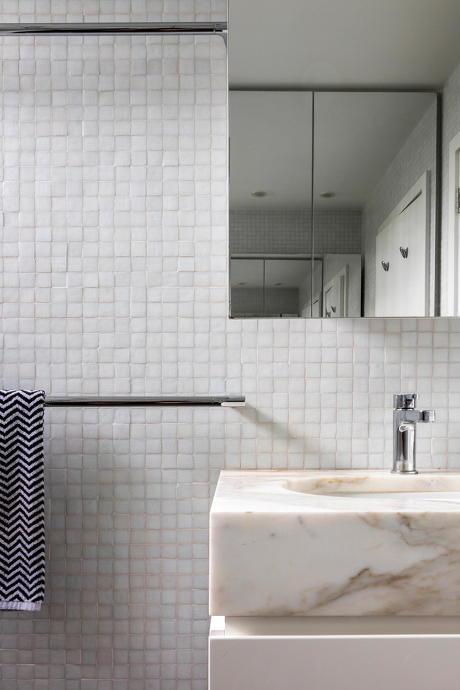 Inspiration for a mid-sized modern kids bathroom in Sydney with furniture-like cabinets, white cabinets, an alcove tub, a shower/bathtub combo, a wall-mount toilet, white tile, mosaic tile, white walls, marble benchtops, an undermount sink and limestone floors.