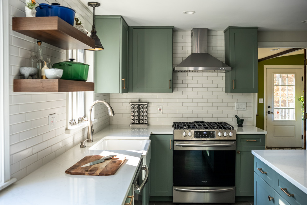 Expansive transitional galley kitchen in Philadelphia with a farmhouse sink, flat-panel cabinets, green cabinets, quartzite benchtops, white splashback, ceramic splashback, stainless steel appliances, vinyl floors, with island, brown floor and white benchtop.
