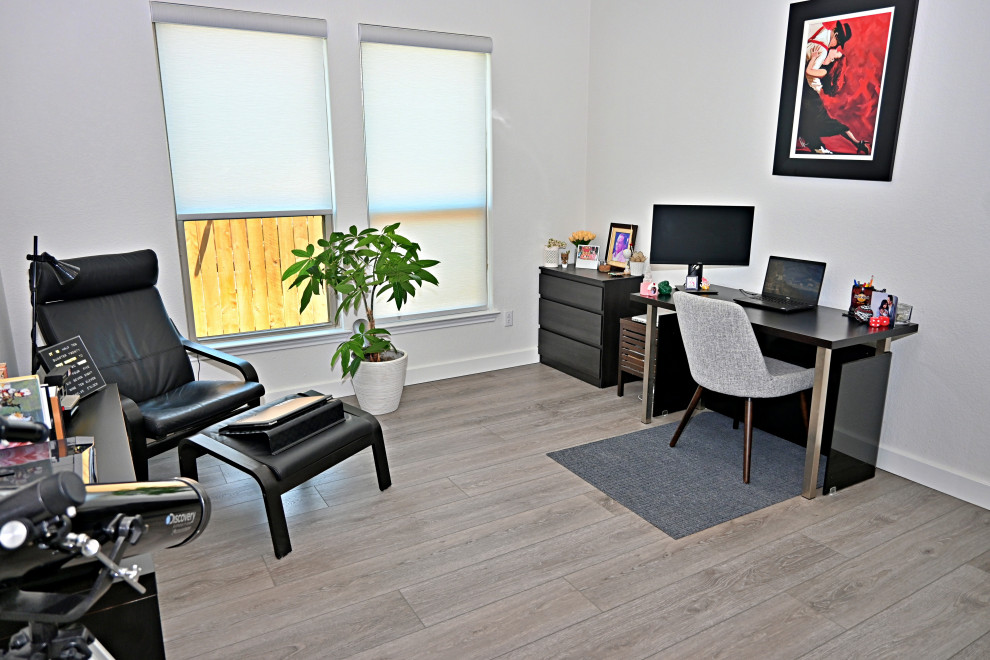 Immagine di un grande atelier contemporaneo con pareti bianche, pavimento in vinile, scrivania autoportante e pavimento grigio