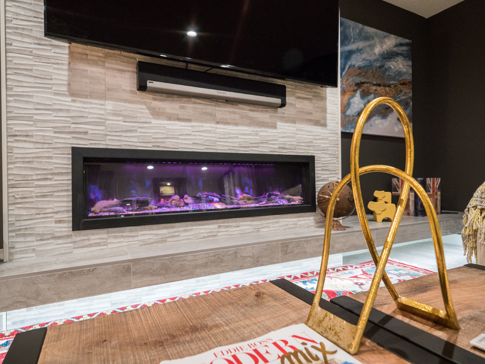 Photo of a mid-sized transitional look-out basement in Other with black walls, carpet, a ribbon fireplace, a tile fireplace surround, brown floor and a home bar.