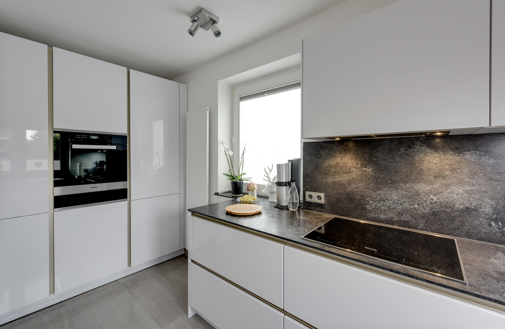 Inspiration for a large contemporary u-shaped kitchen/diner in Hamburg with a built-in sink, flat-panel cabinets, white cabinets, laminate countertops, black splashback, stainless steel appliances, terrazzo flooring, a breakfast bar and beige floors.