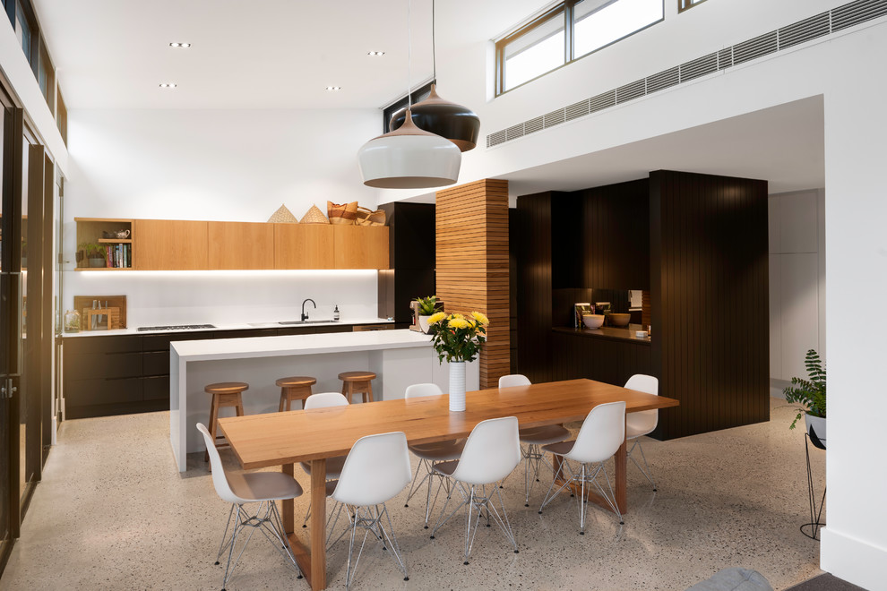 This is an example of a contemporary galley eat-in kitchen in Adelaide with a drop-in sink, flat-panel cabinets, medium wood cabinets, white splashback, concrete floors, with island, grey floor and white benchtop.