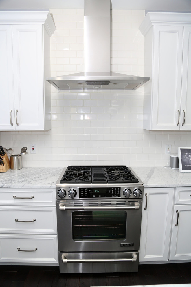 Eat-in kitchen - large transitional l-shaped dark wood floor eat-in kitchen idea in Chicago with recessed-panel cabinets, stainless steel appliances, an island, a farmhouse sink, white cabinets, quartz countertops, white backsplash and subway tile backsplash