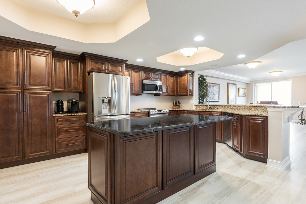 Large traditional l-shaped open plan kitchen in Orlando with an undermount sink, raised-panel cabinets, medium wood cabinets, granite benchtops, stainless steel appliances, vinyl floors, with island, beige floor and beige benchtop.