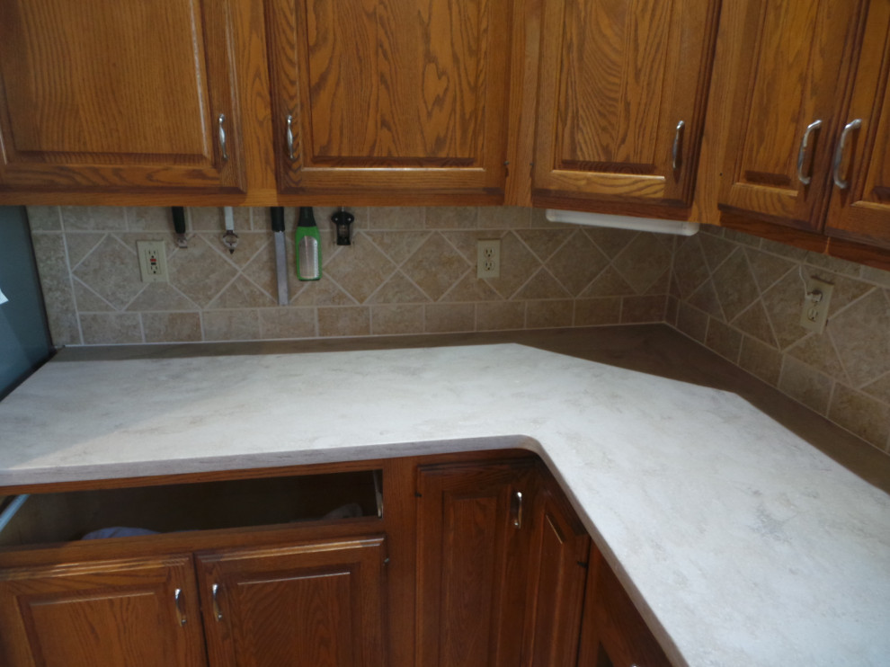 Inspiration for a large contemporary l-shaped light wood floor and brown floor enclosed kitchen remodel with an undermount sink, raised-panel cabinets, medium tone wood cabinets, solid surface countertops, beige backsplash, ceramic backsplash, stainless steel appliances, an island and beige countertops