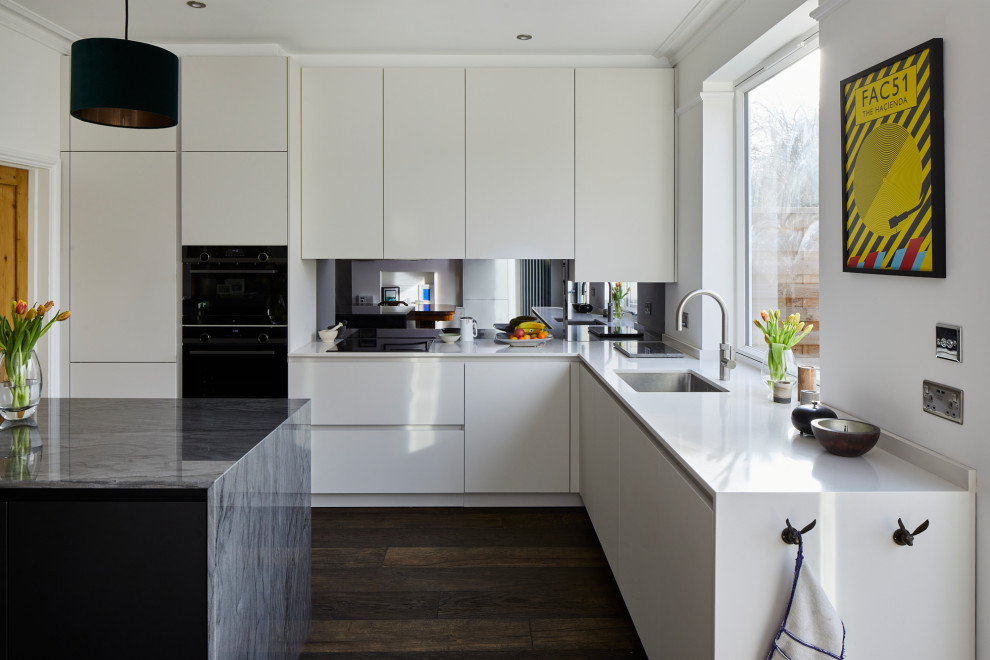 Esempio di una cucina minimalista di medie dimensioni con lavello sottopiano, ante lisce, ante bianche, top in quarzite, paraspruzzi con lastra di vetro, elettrodomestici neri, parquet scuro, pavimento marrone e top bianco