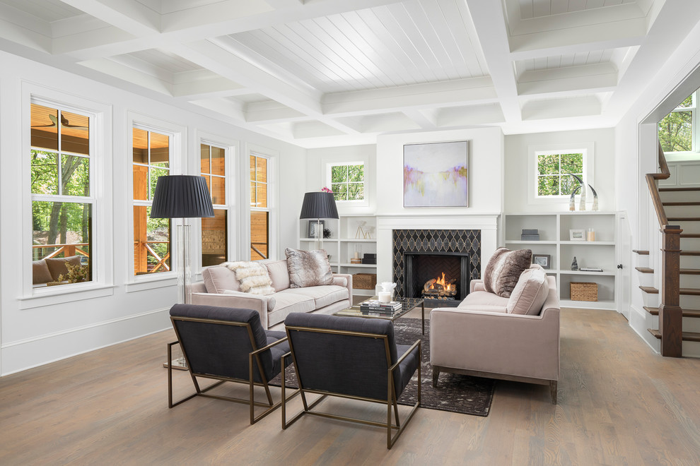 Photo of a country living room in Charlotte with white walls, medium hardwood floors, a standard fireplace, a tile fireplace surround and brown floor.