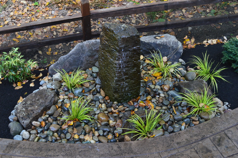 This is an example of a mid-sized craftsman backyard stamped concrete water fountain landscape in Seattle with no cover.