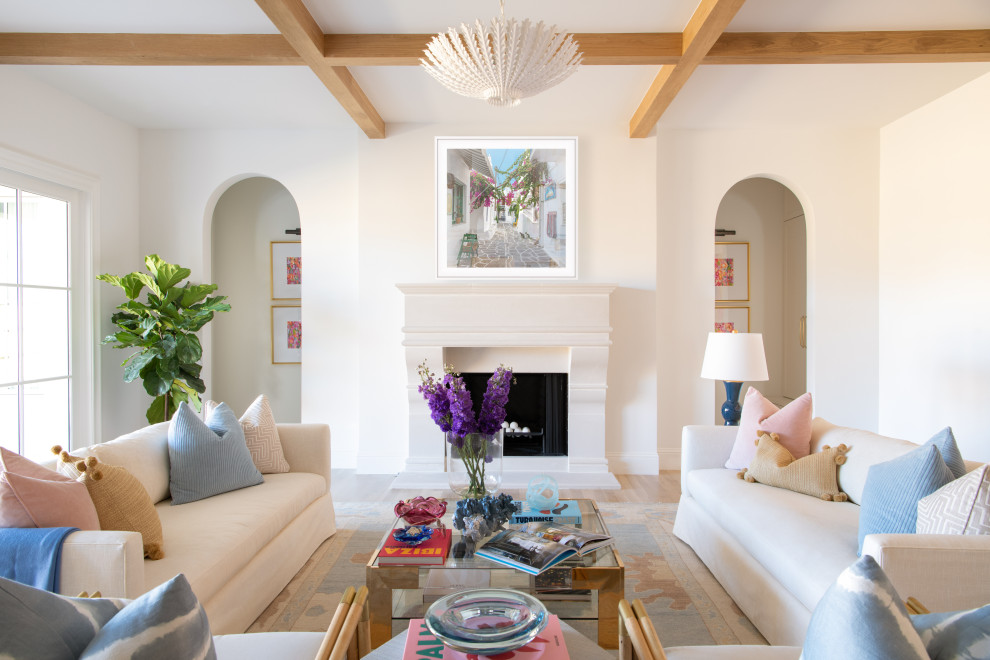 Inspiration pour un grand salon traditionnel ouvert avec un mur blanc, parquet clair, une cheminée standard, un manteau de cheminée en pierre, un sol marron et poutres apparentes.