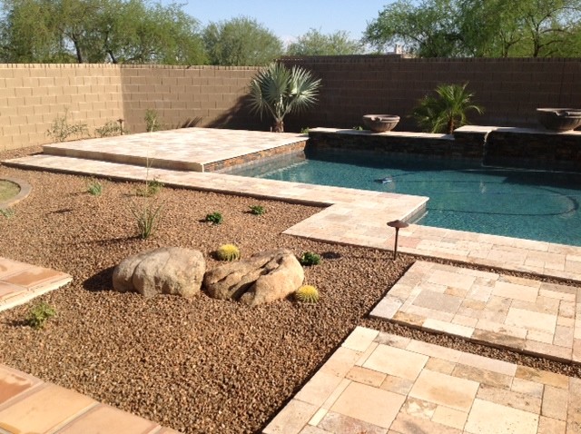 Photo of a large backyard custom-shaped natural pool in Phoenix with a hot tub and natural stone pavers.
