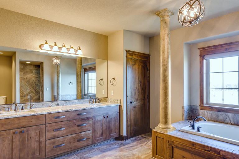 Large mountain style master drop-in bathtub photo with shaker cabinets and medium tone wood cabinets