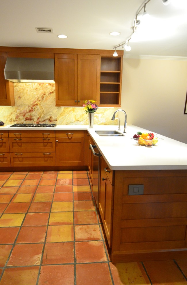 This is an example of a mid-sized transitional u-shaped kitchen in Houston with an undermount sink, shaker cabinets, orange cabinets, quartz benchtops, multi-coloured splashback, stone slab splashback, stainless steel appliances, terra-cotta floors and a peninsula.