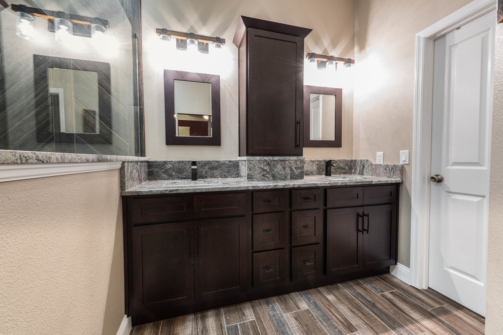 Photo of a mid-sized country master bathroom in Orlando with shaker cabinets, dark wood cabinets, an alcove shower, beige walls, porcelain floors, an undermount sink, granite benchtops, brown floor, an open shower and multi-coloured benchtops.