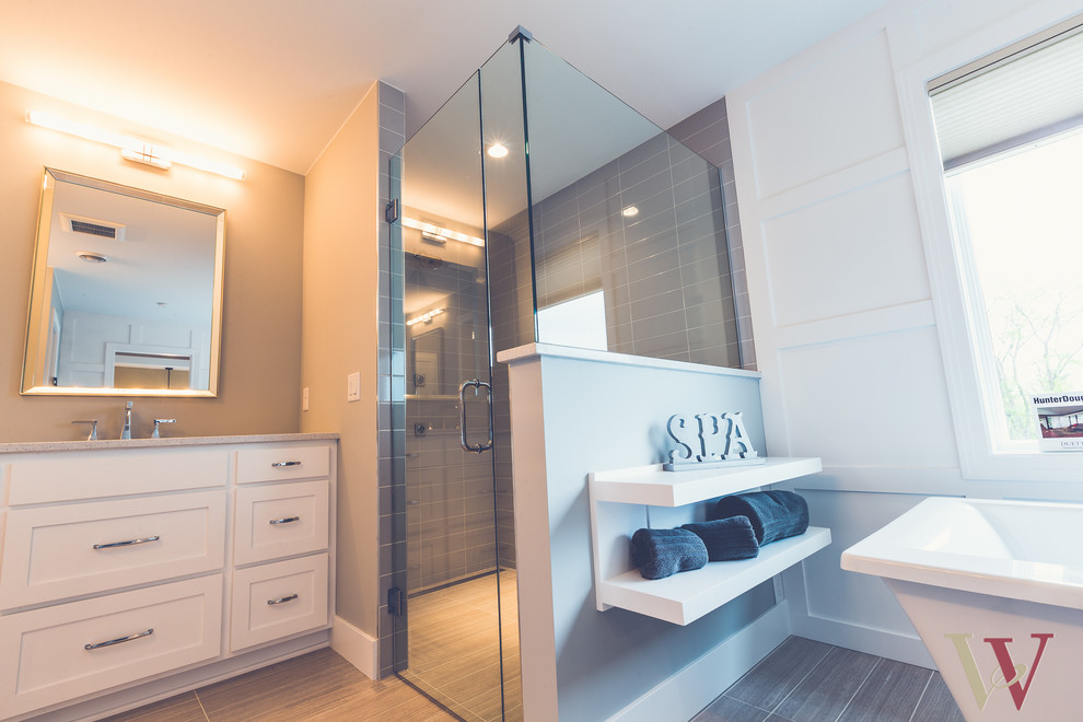 This is an example of a mid-sized country master bathroom in Minneapolis with an undermount sink, flat-panel cabinets, white cabinets, granite benchtops, a freestanding tub, a curbless shower, a one-piece toilet, beige tile, ceramic tile, grey walls and ceramic floors.
