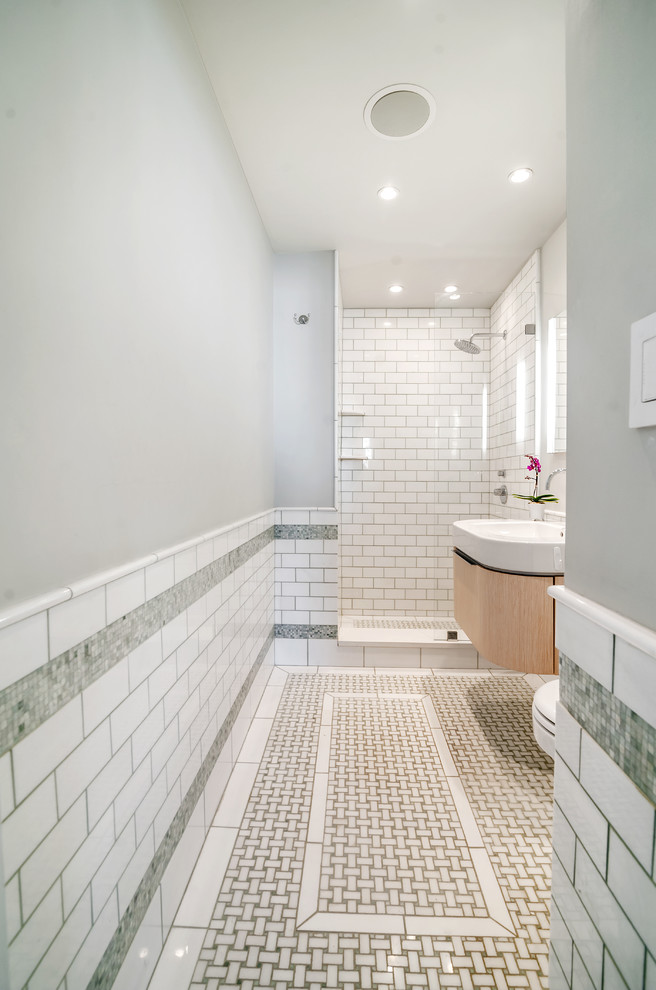 Alcove shower - small contemporary master white tile and subway tile mosaic tile floor alcove shower idea in New York with furniture-like cabinets, light wood cabinets, a wall-mount toilet, green walls, an integrated sink and solid surface countertops